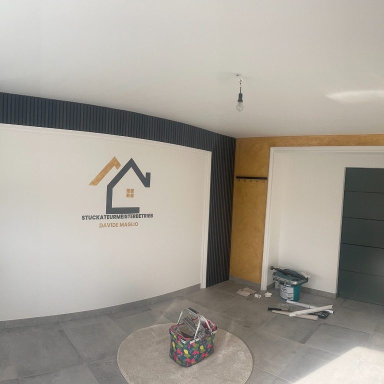 Moderne Raumgestaltung mit Hauslogo an der Wand und Bauzubehör auf dem Boden.